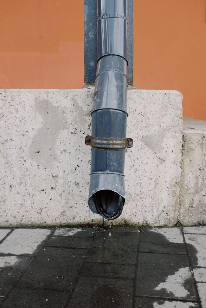Downspout discharging water onto a concrete pad