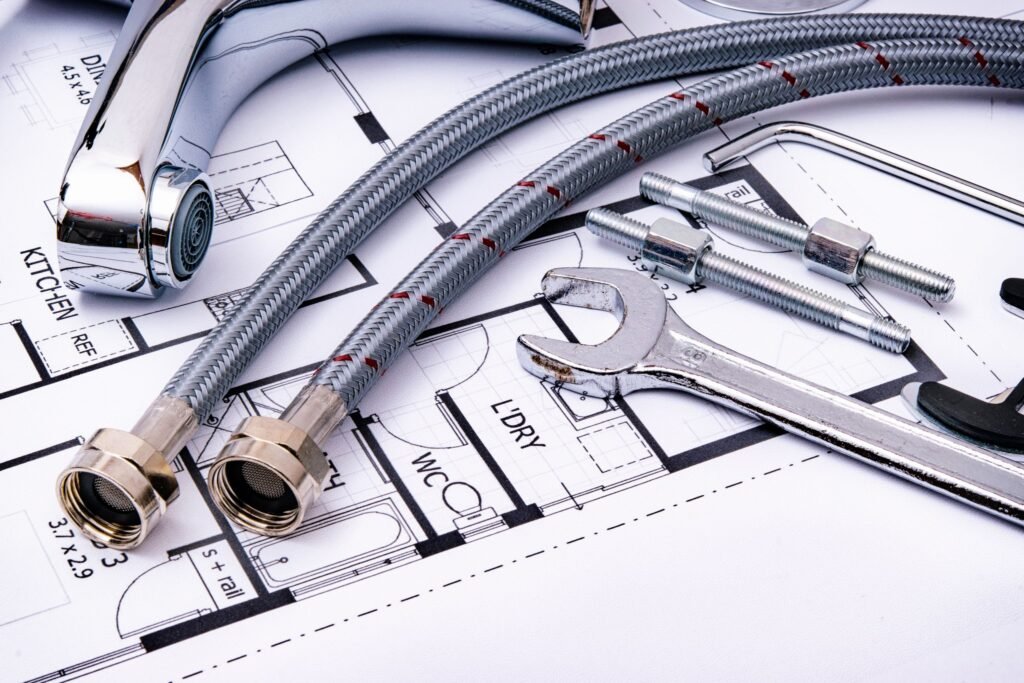 Plumbing tools, braided supply lines, and a wrench on a floor plan