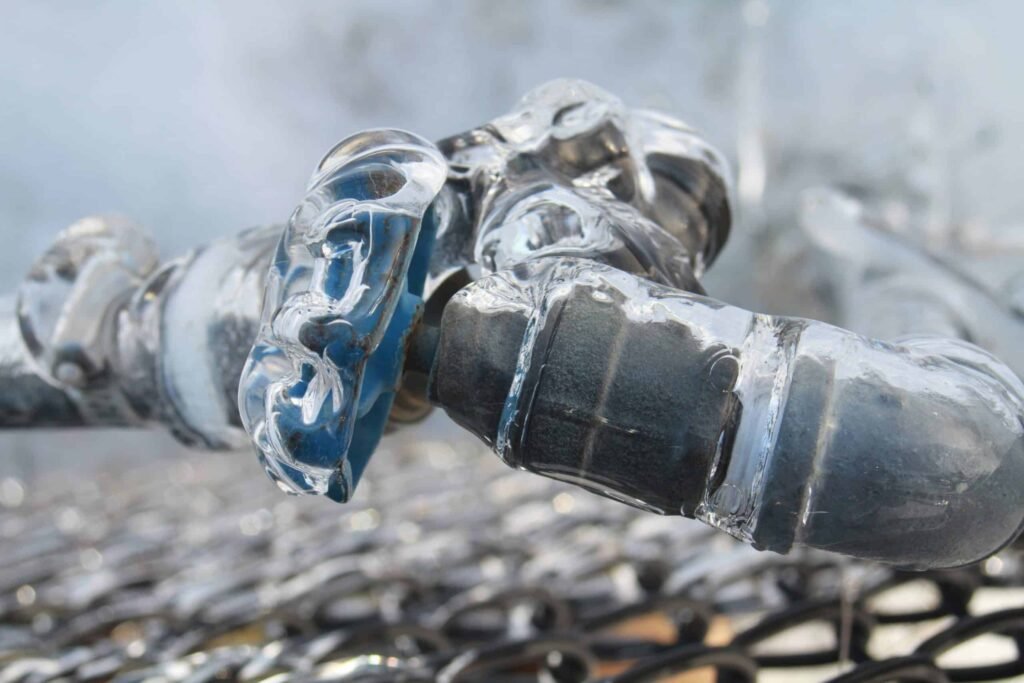 Frozen outdoor pipe fitting covered in ice