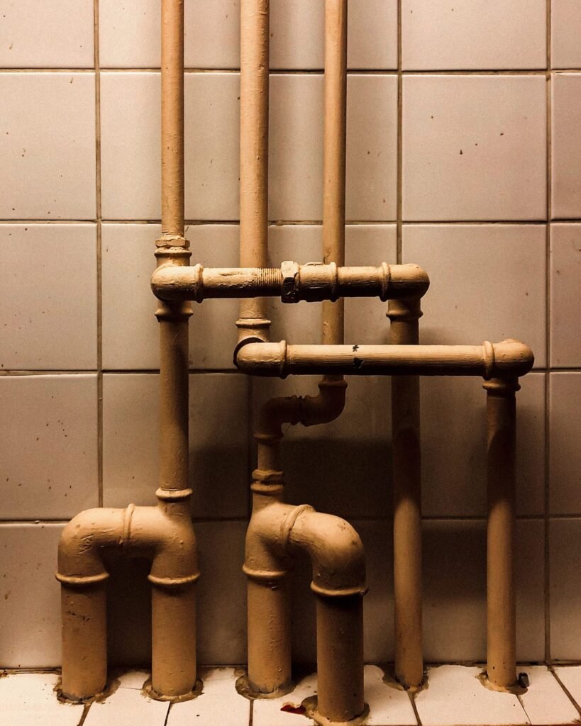 Copper supply and drain piping mounted on a tiled wall